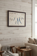 Load image into Gallery viewer, A framed Finger Lakes New York map wall art piece with blue lake outlines and a dark wood frame, mounted on a light gray wall.